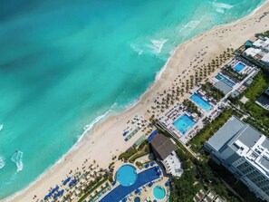 Eine Luftaufnahme eines Strandresorts mit Schwimmbad, Strand und Hotelgebäuden.