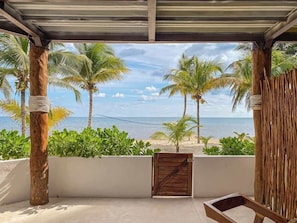 Un espacio al aire libre cubierto con vistas a la playa, palmeras y un portón de madera.