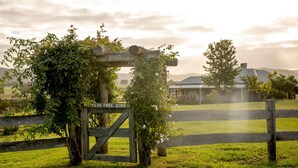 A rustic wooden gate with a sign reading "STRESS FREE ZONE" in a lush green field with a house in the background. - Hanging Tree Homestead - vineyard views, nature & farm animals. Pet-Friendly! (Pokolbin)