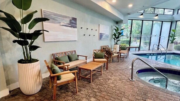 A pool area with seating and a large potted plant. - Cozy Studio near Universal (Orlando)