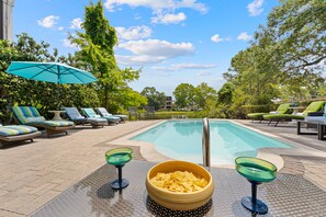 A pool area with lounge chairs, a bowl of chips, and a glass on a table. - 29 Sandcastle Court @ Folly Field Beach | 3D Projector | Pet Friendly | Lagoon Views (Hilton Head Island)