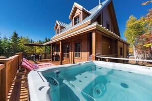 Eine Holzhütte mit Whirlpool, Terrasse und Sitzgelegenheit im Freien.