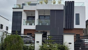 Een modern herenhuis met balkon, grote ramen en een garage.