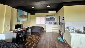 Een kleine hotelkamer met een bed, bureau, computer en kitchenette.