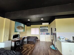 A compact hotel room with a bed, desk, computer, and kitchenette. - Cozy 1-bedroom studio on Capitol Hill Saipan with Ocean View, AC, Wifi (Capitol Hill)