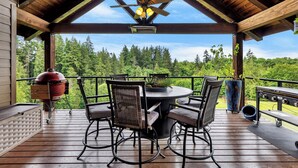Une terrasse extérieure couverte, dotée d’une table ronde et de chaises, d’un ventilateur de plafond et d’un barbecue.