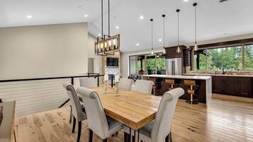 Une cuisine moderne dotée d’un grand îlot central, d’une table à manger en bois et de luminaires suspendus.