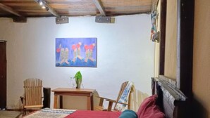 Een kamer met een bed, een houten plafond, een schilderij aan de muur en een kleine tafel met een plant.