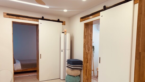 Una camera da letto moderna con un letto, un armadio e una piccola zona relax con cuscini.