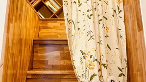Una scala in legno con una libreria a muro e una tenda floreale.