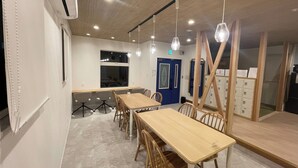 A conference room with a long table, chairs, and hanging pendant lights. - TINY HOTEL YADORIGI KAMIGOTO (Shinkamigoto)