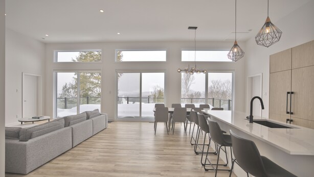 A modern kitchen with a large island, bar stools, and a view of the outdoors.