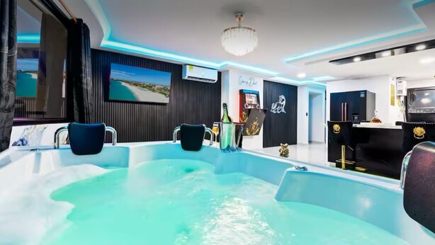 Un espace spa moderne doté d’un grand jacuzzi, d’une télévision et d’un mini-bar.