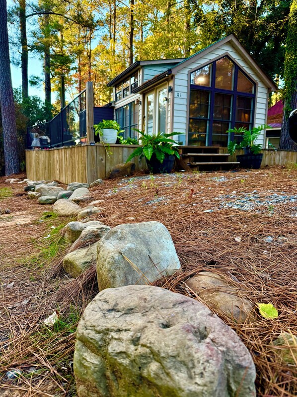 A cabin with a wooden deck, large windows, and potted plants.