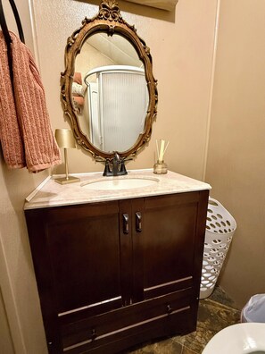 A bathroom with a dark wooden vanity, a large mirror, a white sink, and a towel rack with pink towels.