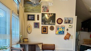 Cozinha com piso de madeira, área de bar com banquetas e obras de arte penduradas na parede.