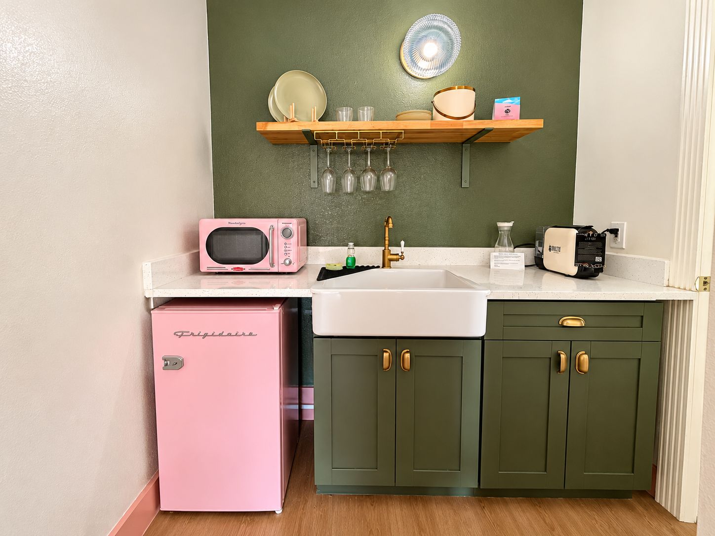 Una cocina compacta con un refrigerador rosa, un microondas y un lavamanos.