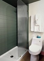 Un baño con cabina de ducha, inodoro y toallero.
