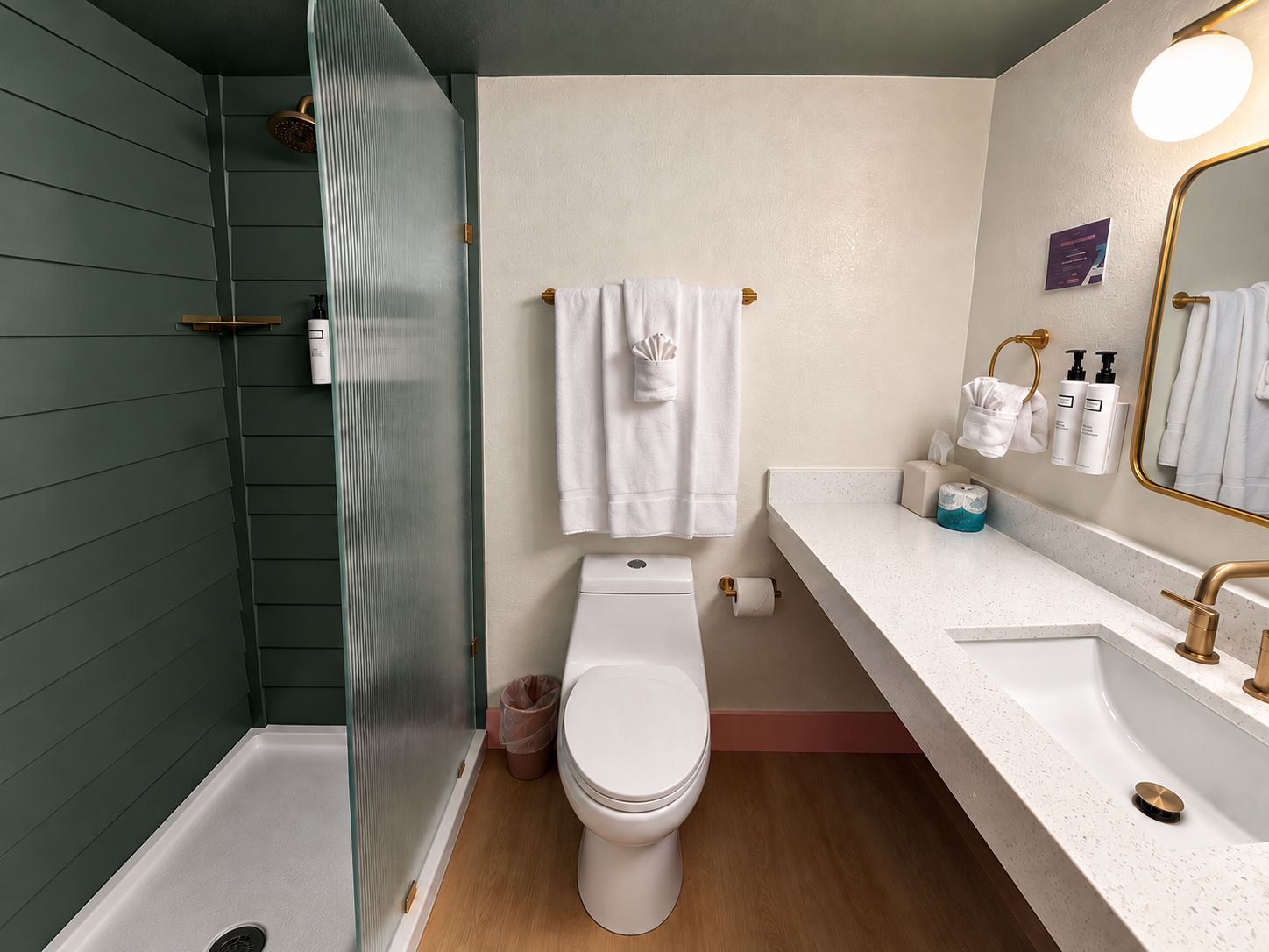 A bathroom with a shower, toilet, sink, and a mirror.