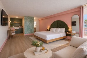 A hotel room with a bed, a sofa, a dining area, and a view of the pool. - Abode Beach House (Clearwater Beach)
