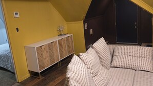 Un dormitorio con cama, una consola blanca, un sofá y una puerta.
