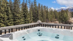 Un jacuzzi en una terraza con un bosque y montañas al fondo.