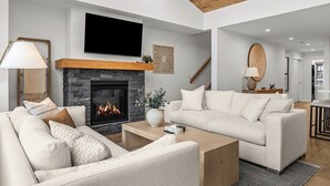 Una sala de estar moderna con chimenea, televisor de pantalla plana y un sofá grande.