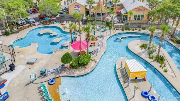 Et resortområde med swimmingpool, flere vandinstallationer, palmer og en bygning med skiltet "River City".