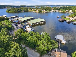 En småbåtshamn med förtöjda båtar, en byggnad med ett grönskande tak och ett skogsområde.
