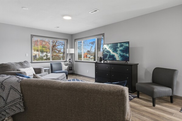 A modern living room with a sofa, armchairs, a TV, and a cabinet. - Charming & Cozy Waterfront Cabin at 21mm Near Shorty Pants (Osage Beach)