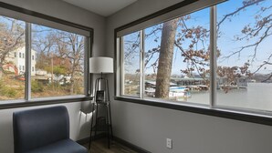 Ein Zimmer mit großem Fenster, blauem Sessel und Stehlampe.