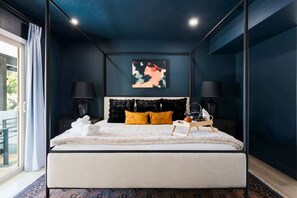 Ein modernes Schlafzimmer mit Bett, schwarzem Kopfteil, zwei Nachttischlampen, einem gerahmten Kunstwerk und einem Fenster mit Vorhängen.