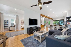 Ein modernes Wohnzimmer mit Flachbildfernseher, dunklem Sofa, Couchtisch und Deckenventilator.