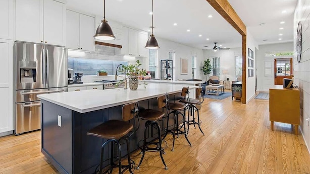 Una cocina moderna con una isla grande, electrodomésticos de acero inoxidable y taburetes de bar.