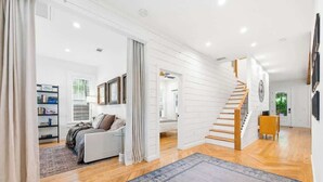 Un salón espacioso con escalera, un sofá y una estantería.