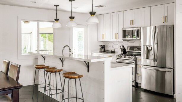 A modern kitchen with white cabinetry, stainless steel appliances, and a central island with bar stools. - Bello Grove | Old Town w/ Pool, Putting Green, Pinball & Games (Scottsdale)
