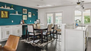 A modern kitchen with white cabinets, a teal accent wall, and a dining area with a wooden table and chairs. - Bello Grove | Old Town w/ Pool, Putting Green, Pinball & Games (Scottsdale)