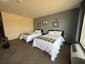 Una habitación de hotel con dos camas, un radiador portátil y una ventana con cortinas.