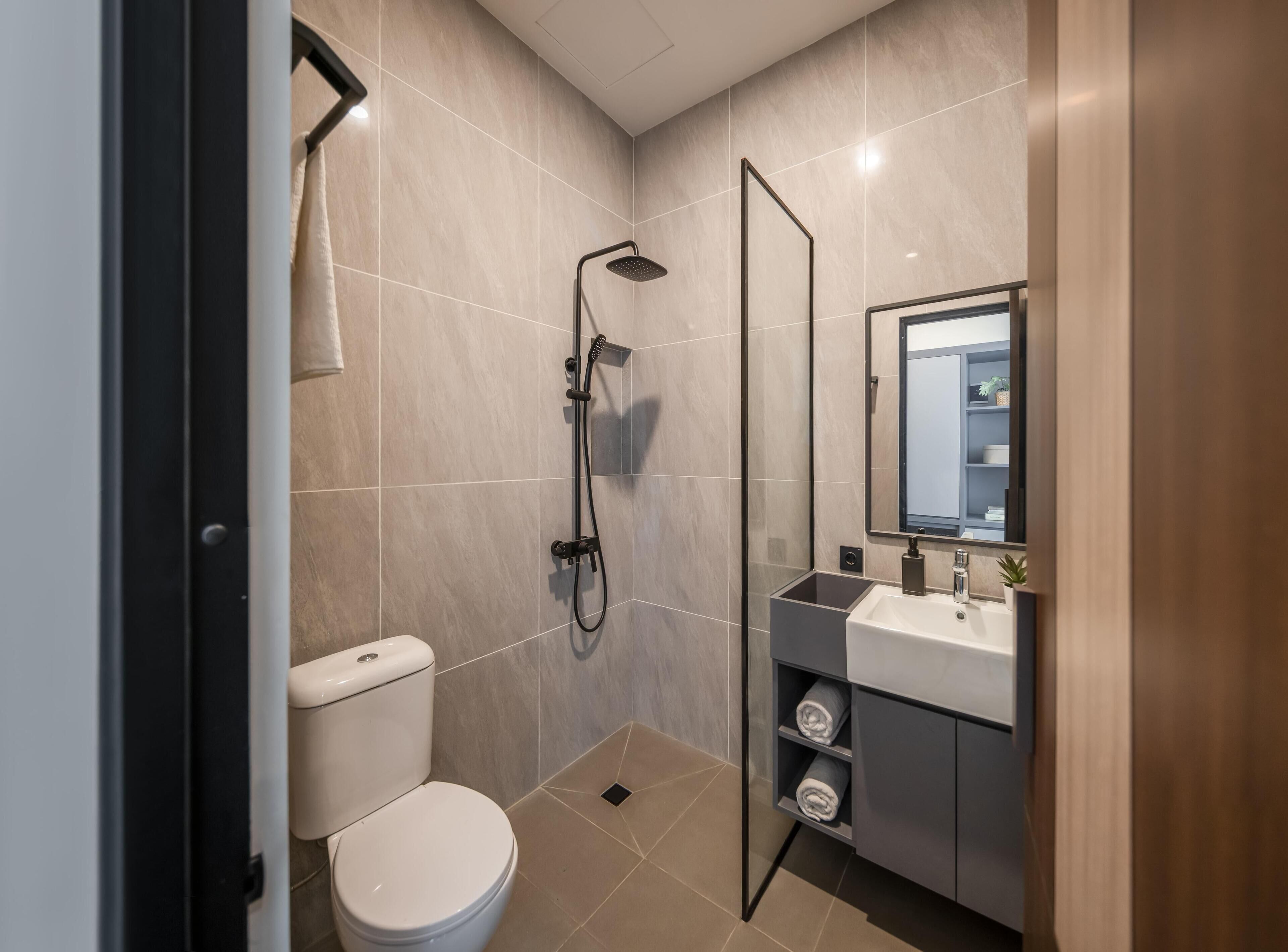 Un baño moderno con inodoro, ducha y tocador con espejo.