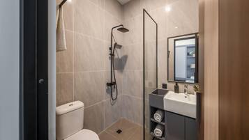 Un baño moderno con inodoro, ducha y tocador con espejo.