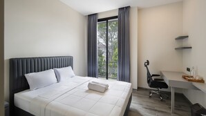 A modern hotel room with a large bed, a desk, and a view of the outdoors. - Cove Legacy (Jakarta)