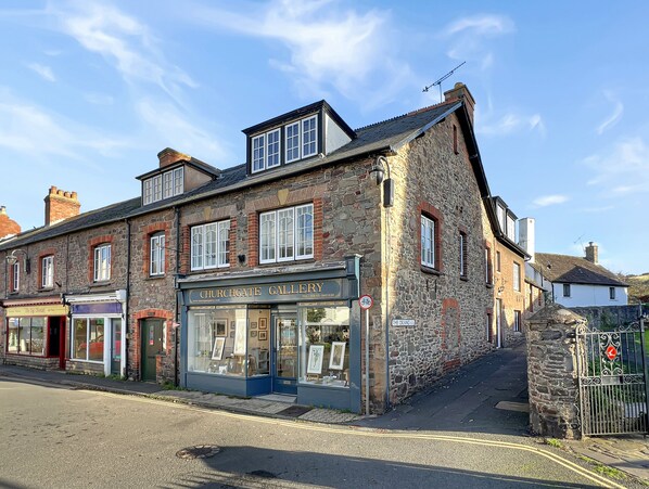 A two-story stone building with a sign for 'CHURCHGATE GALLERY'. - Oxford House, Porlock (Porlock)