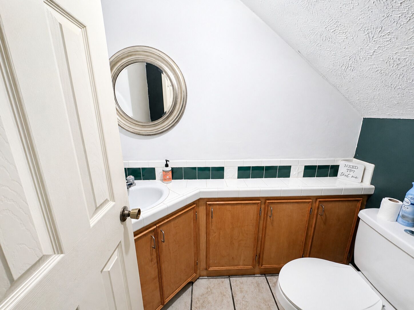 Un baño con un lavamanos blanco, armarios de madera, un inodoro y un espejo.
