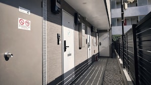 A corridor with doors, a no-smoking sign, and a security camera. - Yue Stay Komagome (Tokyo)