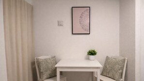 A small, white table with two chairs, each with a patterned cushion. A framed artwork hangs on the wall above the table. - Yue Stay Komagome (Tokyo)