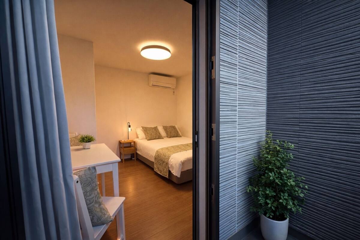 A modern bedroom with a bed, bedside table, and a potted plant.