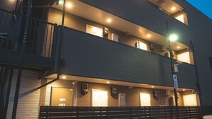 A multi-story building with balconies, external lighting, and a sign indicating a business center. - Yue Stay Komagome (Tokyo)
