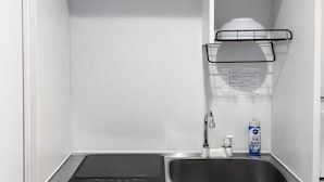 A compact kitchen with a built-in dishwasher, a stainless steel sink, and a black countertop. - Yue Stay Komagome (Tokyo)