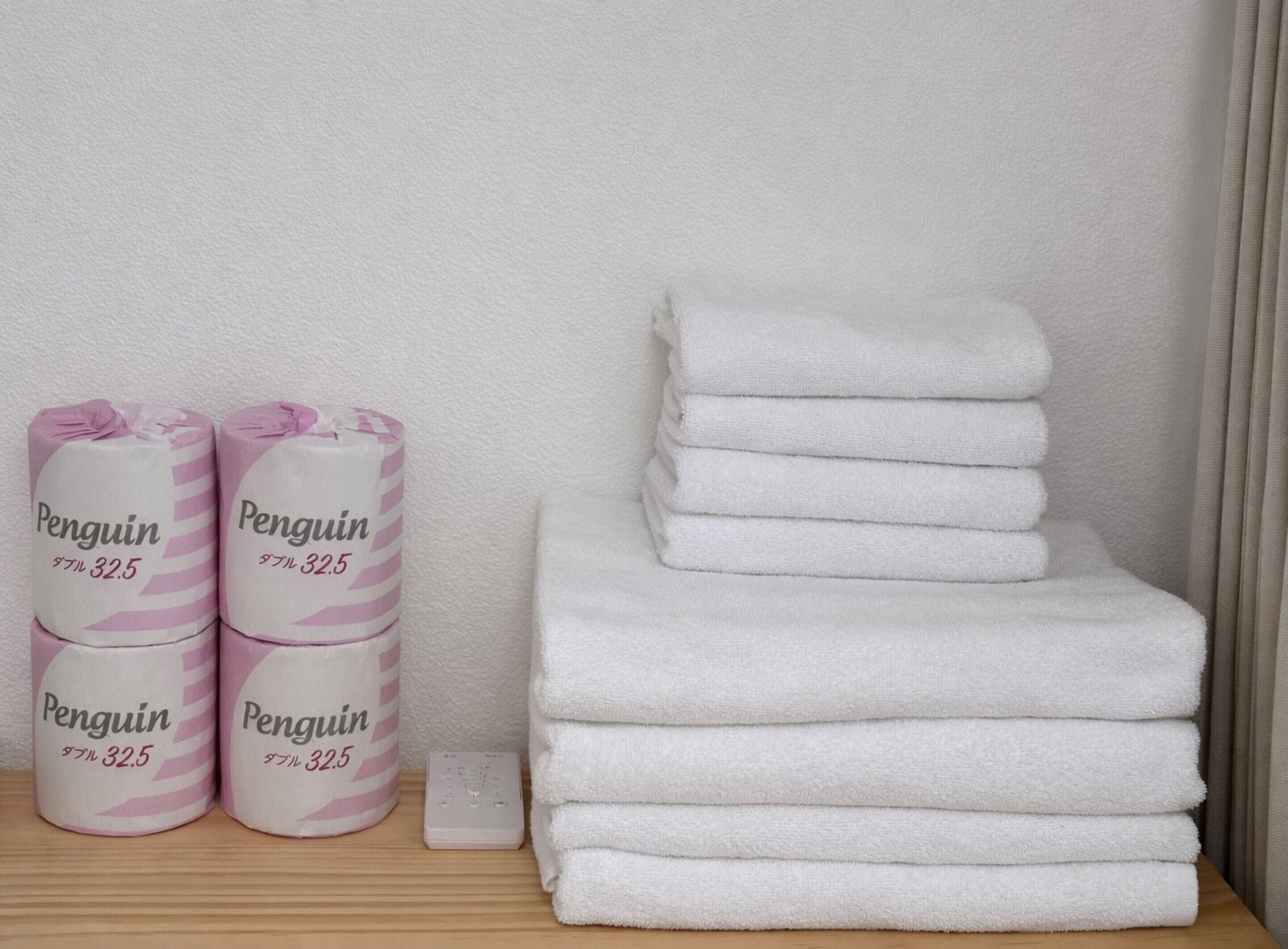 A stack of white towels and three rolls of pink and white striped towels labeled "Penguin 32.5".