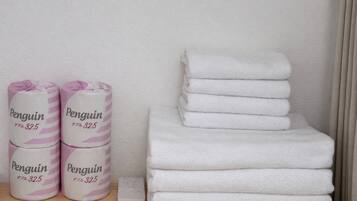 A stack of white towels and three rolls of pink and white striped towels labeled "Penguin 32.5".